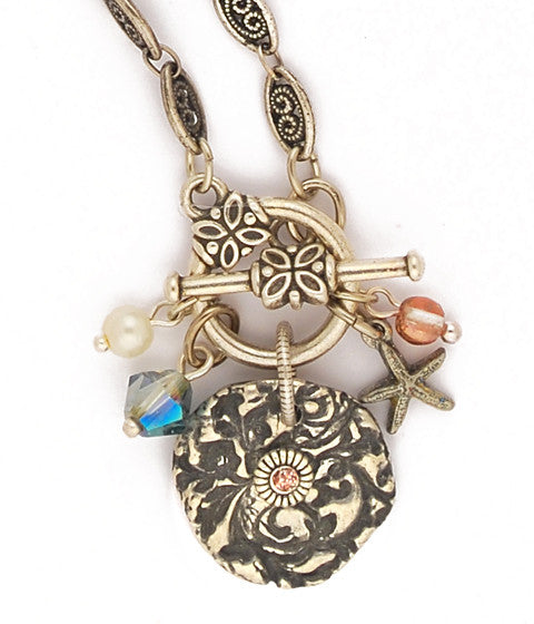 Original cast pewter design with sparkly copper colored enamel, Swarovski creme rose glass pearls, apollo gold glass beads, iridescent blue/green crystal, sterling plated & antiqued brass starfish, woven brass chain that has been sterling plated and then antiqued. Front toggle closure. 18" long